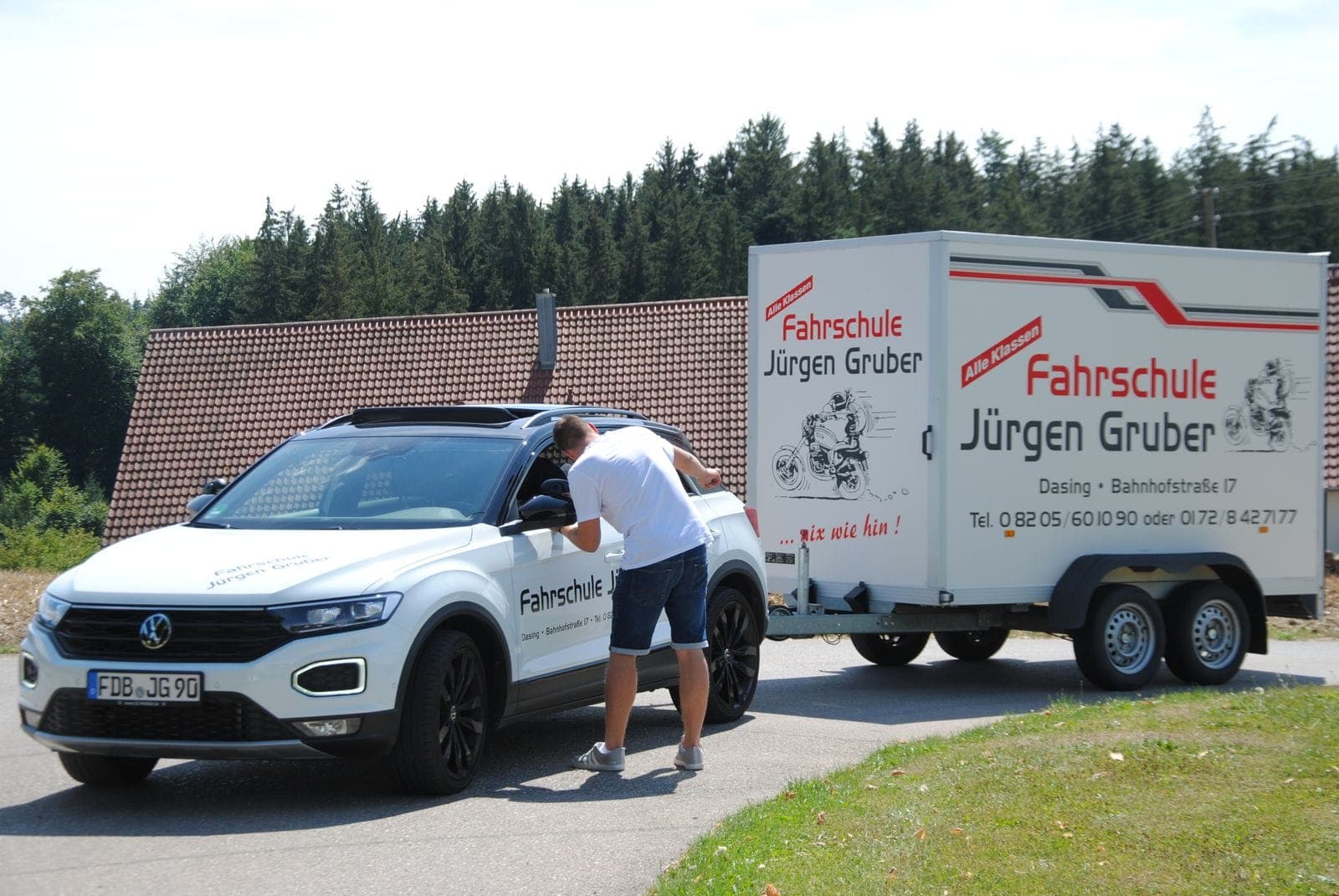 Fahrschul-SUV mit Motorrad-Anhänger und der Aufschrift „… nix wie hin!“