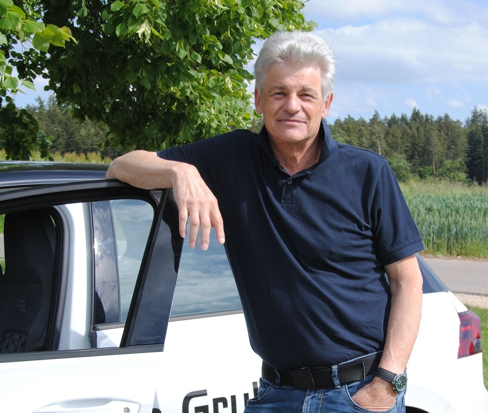 Fahrlehrer Günter Jarosch am weißen Fahrschulauto