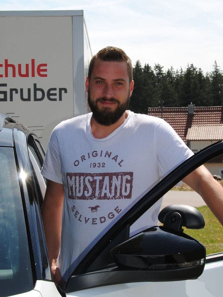 Michael Mangold an der offenen Tür des Fahrschul-SUV vor dem beschrifteten Anhänger